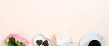 Sevgililer günü afişi. Düz kompozisyon gülleri, kalp şeklinde şekerler, pastel bej arka planda hediye kutusu ve kahve fincanı. Sevgililer Günü, aşk, aşk konsepti.