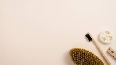Sıfır atık banyo aksesuarı seti. Fırça, diş fırçası, luffa süngeri ve ahşap broşla en az düz konum kompozisyonu. Doğal organik kaplıca kozmetik araçları, çevre dostu konsept.
