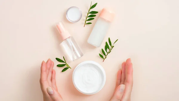 Pot de crème pour les mains bio, bouteille d'huiles essentielles et feuilles vertes sur fond beige. Soin de la peau, concept de produits de beauté naturels bio — Photo