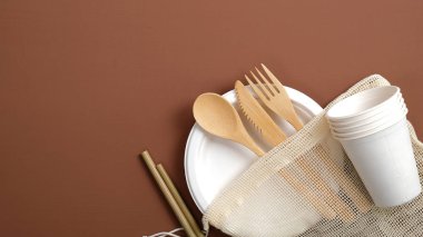 Yeniden kullanılabilir kaplar ayarlandı. Bambu çatal bıçak takımı, karton bardaklar ve tabaklar, kahverengi arka planda pamuk örgüsü. Fotokopi alanı olan eko mağaza afişi. Sıfır atık. Sürdürülebilir yaşam tarzı.