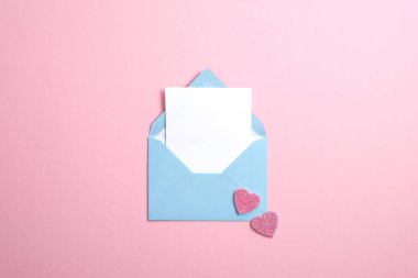 İçinde beyaz bir not olan mavi bir zarf ve pembe arka planda sevgililer günü kalpleri. Sevgililer Günü konsepti için romantik aşk mektubu.