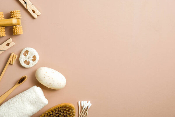 Natural bathroom accessories, organic spa and beauty treatment products on brown background. Zero waste, plastic free concept. Flat lay homemade soap, bamboo toothbrush, wooden pins, luffa sponge.