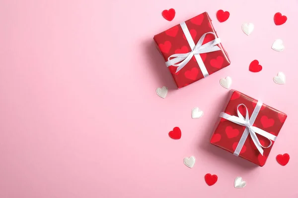 Due scatole regalo rosse con fiocco a nastro e cuori di San Valentino su sfondo rosa con spazio copia. Stendardo o biglietto di auguri per San Valentino. Posa piatta, vista dall'alto . — Foto Stock