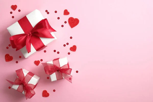 Cajas de regalo envueltas en papel blanco con lazo de cinta roja y corazones de San Valentín sobre fondo rosa. Asiento plano, vista superior. Banner o tarjeta de felicitación maqueta para San Valentín o el Día de la Madre . — Foto de Stock