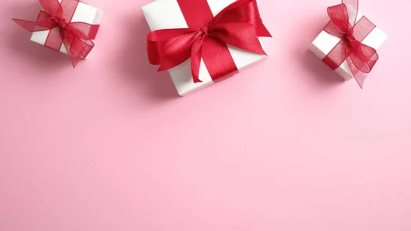 Tarjeta San Valentín con cajas de regalo blancas decoradas con lazo de cinta roja sobre fondo rosa. Piso tendido, vista superior . —  Fotos de Stock