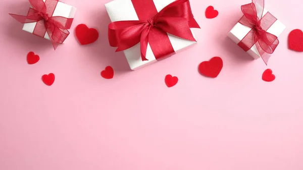 Valentijnsdag concept. Roze achtergrond met witte geschenkdozen en rode hartjes. Vlakke lay, bovenaanzicht. — Stockfoto