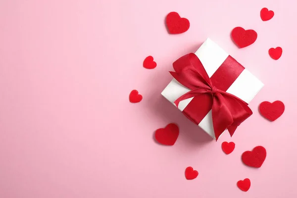 Feliz día de San Valentín maqueta de tarjetas. Caja de regalo blanca con lazo de cinta roja y corazones rojos sobre fondo rosa. San Valentín, aniversario, día de la madre y saludo de cumpleaños. Plano, vista superior, techo . — Foto de Stock