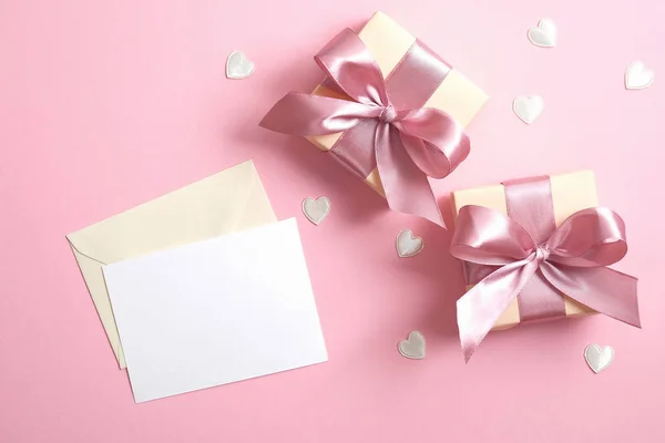 Romantiskt kärleksbrev med vit papper not mockup och två presentaskar med band båge på rosa bakgrund dekorerade Alla hjärtans hjärtan. Minimal platt låg stil sammansättning, ovanifrån. — Stockfoto
