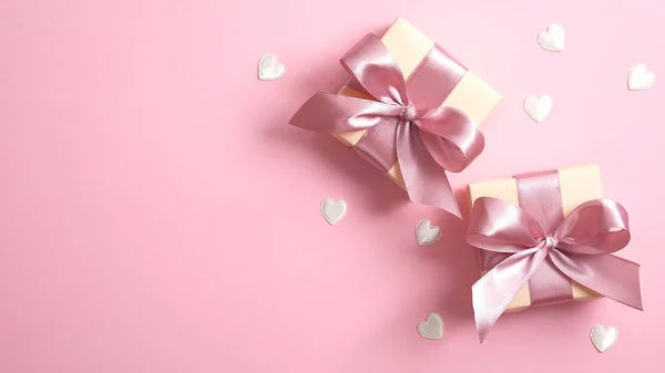 Twee geschenkdozen met roze lint strik, en valentijnskaarten harten op roze achtergrond. Vlakke lay, bovenaanzicht. Gelukkige Valentijnsdag of Moederdag spandoek model. — Stockfoto