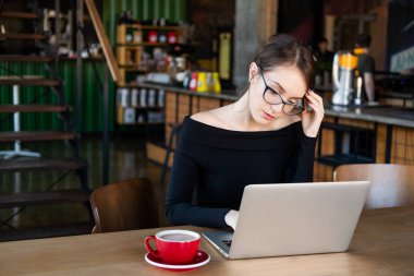 Kafede dizüstü bilgisayarla çalışan odaklanmış bir kadın