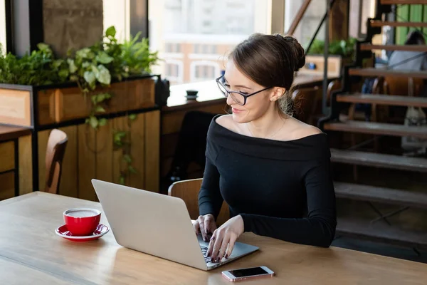 Junge Frau arbeitet im Café am Laptop — Stockfoto