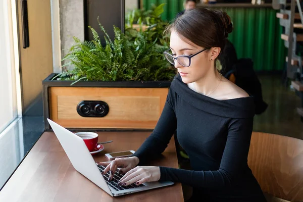 Donna freelance che lavora su un computer portatile in un bar. Concetto di lavoro a distanza e lavoro remoto — Foto Stock
