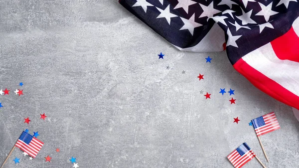 US American flags and confetti star on concrete stone background with copy space. Banner mockup for Presidents day, USA Memorial day, Veterans day, Labor day, or 4th of July celebration.