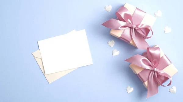 Sevgililer günün kutlu olsun. Pembe kurdeleli hediye kutuları ve pastel mavi arka planda kalp şeklinde konfetileri olan boş kartpostallı romantik mektuplar.. — Stok fotoğraf