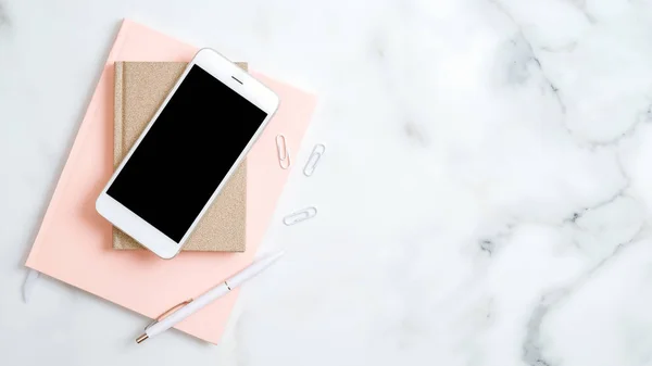 Домашній офісний стіл робочий простір з макет екрану смартфона, рожева блокнот, ручка на мармуровому фоні. Плоский простір, вид зверху. Елегантне жіноче робоче місце зі стильними аксесуарами — стокове фото
