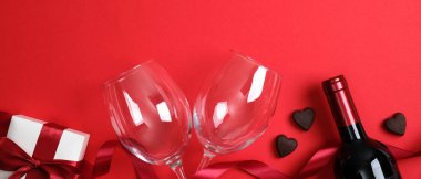 Sevgililer Günü arkaplanı, şarap şişesi şampanya, iki bardak kırmızı kurdele şeklinde şeker dolu beyaz hediye kutusu. Sevgililer Günü için en iyi manzara masası. Romantik yemek çifti konsepti