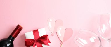 Sevgililer Günü afiş şablonu kutlu olsun. Üst manzara şarap şişesi şampanya, hediye kutusu, iki bardak ve pembe arka planda kalp süslemesi. Sevgililer Günü kutlaması, aşk, romantik akşam yemeği çifti konsepti