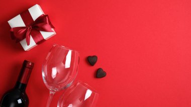 Sevgililer Günü yemeği konsepti. Romantik akşam yemeği, bir şişe şarap şampanyası, bardaklar, beyaz hediye kutusu, şekerler. Sevgililer günü kartı. Kopya alanı olan Sevgililer Günü afişi.