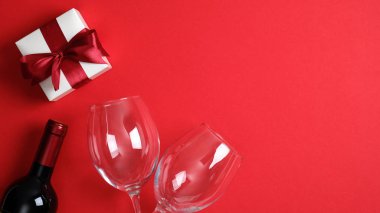 Sevgililer Günü arkaplanında bir şişe şarap şampanya, bardak ve sevgililer günü hediyesi var. Düz konum, üst görünüm, kopyalama alanı. Sevgililer Günü konsepti için romantik yemek masası..