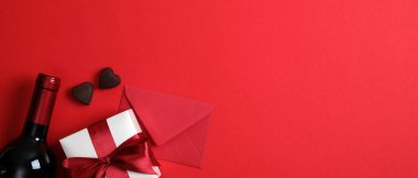 Sevgililer günü afişi, şarap şişesi, kırmızı zarf, sevgililer günü hediyesi, kırmızı arka planda fotokopi alanı olan kalp şeklinde şekerler. Üst manzara, düz yatış. Romantik yemek çifti konsepti