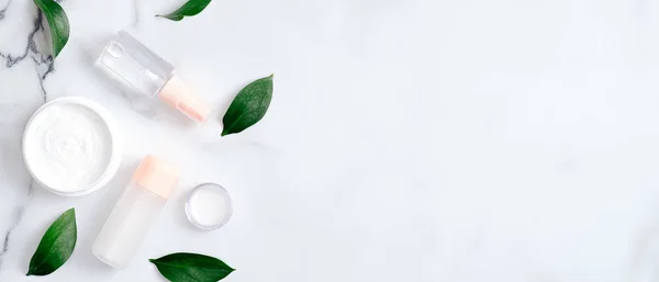 Natuurlijke biologische cosmetische lotion flessen en handcrème op marmeren achtergrond met groene bladeren. Platte lay, bovenaanzicht, kopieerruimte. Schoonheidsblog banner sjabloon. Handhuidverzorging, lichaamsverzorging concept — Stockfoto