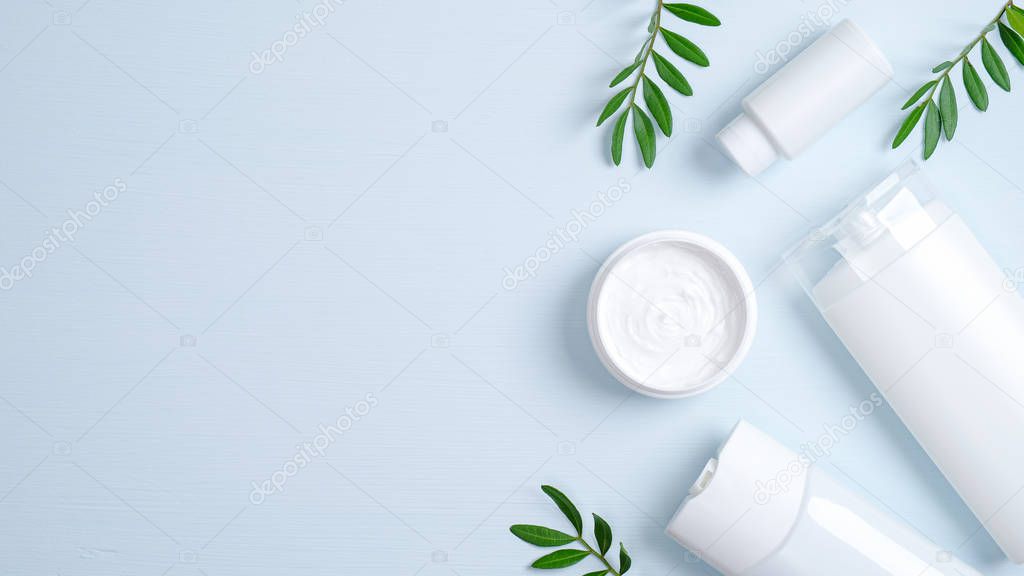 Natural organic cosmetic products concept. Hair care herbal cream in jar, shampoo bottle, shower gel container and green leaves. SPA cosmetic packaging branding mockup. Flat lay minimalist style set