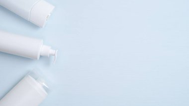 Spa kozmetik ürünleri markalaştırma modeli. Şampuan ambalajı, duş jeli için temiz bir şişe mavi arka planda sıvı sabun için pompa şişesi. Minimalist tarzda dümdüz yatıyordu. Doğal güzellik ürünü konsepti