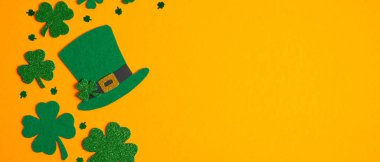 Turuncu arka planda Aziz Patrick günü sembolleri. İrlanda elf şapkası ve yonca yonca sembolleri. Aziz Patrick Günü konseptin kutlu olsun. Tebrik kartı, parti davetiyesi şablonu, pankart modeli