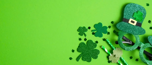 Diseño de pancartas del Día de San Patricio. Gafas de fiesta de vista superior, pajitas para beber y tréboles de hojas de trébol sobre fondo verde con espacio para copiar. Concepto de feliz día de San Patricio —  Fotos de Stock