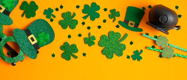 San Patricks borde marco del día de trébol de cuatro hojas, sombrero de elfo irlandés, olla de oro, gafas de fiesta sobre fondo naranja. Feliz concepto del Día de San Patricio. Plantilla de tarjeta de felicitación, maqueta de banner —  Fotos de Stock