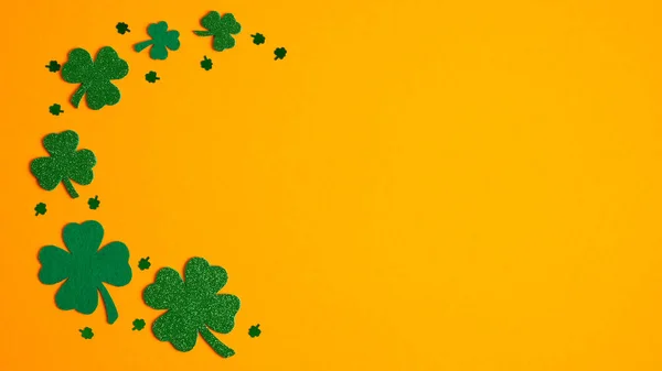 St Patricks Day borde marco de trébol y tréboles de cuatro hojas sobre fondo naranja. Asiento plano, vista superior. Diseño de pancartas, maqueta de tarjetas de felicitación. Concepto de Feliz Día de San Patricio — Foto de Stock