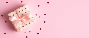 Pembe arka planda, konfetili bir hediye kutusu. Sevgililer Günü hediyesi ya da doğum günü hediyesi konsepti. Düz yerde, üst tarafta. Sevgililer Günü afiş şablonu
