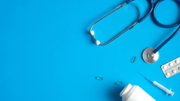 Medische apparatuur, gereedschap, benodigdheden op blauwe achtergrond. Platte stethoscoop, spuiten, pillen. Medisch spandoek ontwerp. Begrip gezondheidszorg en geneeskunde. — Stockfoto