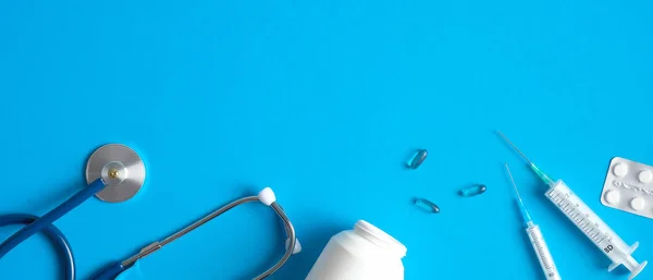 Bannière d'équipement médical avec stéthoscope, pilules, seringue sur fond bleu. Couché à plat, vue de dessus. Soins de santé et concept médical . — Photo