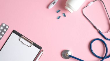 Pembe arka planda tıbbi ekipman. Doktor masasının üstünde tıbbi pano, kalem, hap, termometre, stetoskop var. Tıbbi afiş şablonu, başlık modeli. Sağlık ve Tıp Konsepti