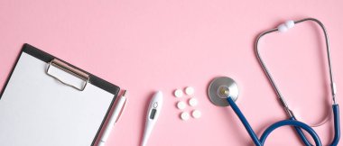 Pembe arka planda tıbbi ekipman ve aletler. Doktor masasının üstünde tıbbi dosya, steteskop ve haplar var. Sağlık ve tıp konsepti. Tıbbi afiş şablonu, başlık modeli