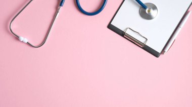 Stetoskop ve pembe arka planda kalem olan tıbbi pano. Düz yerde, üst tarafta. Tıbbi afiş şablonu, başlık modeli. Sağlık ve Tıp Konsepti
