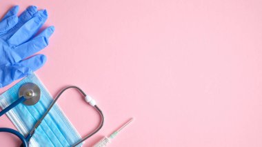 Pembe arka planda tıbbi ekipman ve aletler. Üst düzey steteskop, cerrahi maske, tıbbi eldivenler, pembe arka planda fotokopi alanı olan şırınga. Sağlık ve tıp konsepti. Tıbbi afiş tasarımı