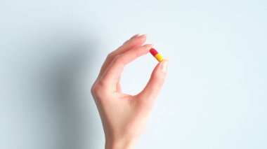 Kadın el hapları ya da vitamin hapları mavi arka planda kapsülde. Eczane ve ilaç konsepti
