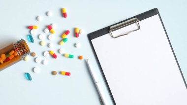 İçinde haplar ve cam bir şişeden dökülen kapsüller olan boş bir tıbbi dosya. Doktor masası üst görünümü. Eczane ve ilaç konsepti