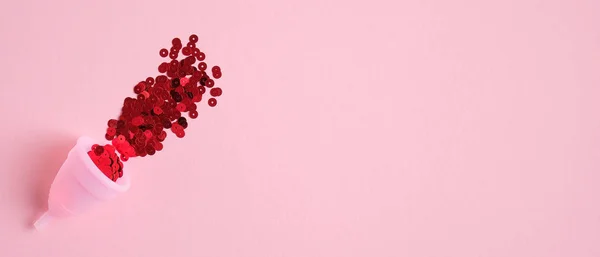 Copo menstrual preenchido confete vermelho no fundo rosa com espaço de cópia. Design de banner para blog de beleza. Produto de higiene menstrual alternativo. Dias críticos, ciclo menstrual, conceito de saúde feminina — Fotografia de Stock
