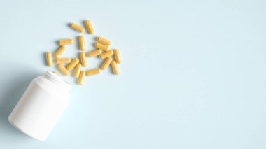 Dağınık haplar ve beyaz şişe mavi arka planda fotokopi alanı var. Üst Manzara. Sağlık, ilaç ve eczane konsepti