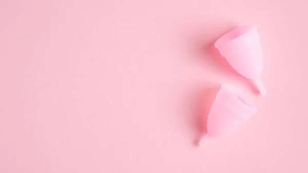 Menstruationskoppar på rosa bakgrund. Ovanifrån med kopieringsutrymme. Alternativa feminina hygienprodukter. Begreppet kvinnohälsovård. — Stockfoto