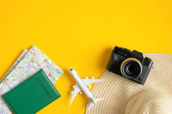 Аксессуары для путешествий на желтом фоне. Плоская винтажная камера, пляжная шляпа, карта, паспорт, самолет. Вид сверху с пространством для копирования. Концепция планирования летнего отдыха — стоковое фото