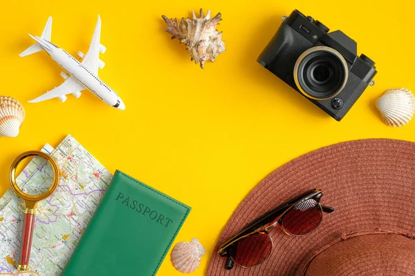 Плоские аксессуары на желтом фоне с винтажной камерой, моделью самолета, пляжной шляпой, паспортом, картой, увеличительным стеклом и морскими пейзажами. Концепция путешествия или отпуска с видом сверху. Летний фон — стоковое фото