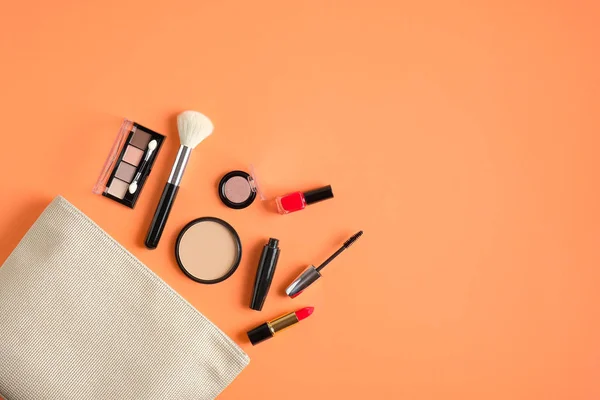 Borsa per il trucco con prodotti cosmetici che si rovesciano su sfondo color pesca pastello. Posa piatta, vista dall'alto. Elegante borsa make up artist con prodotti di bellezza — Foto Stock