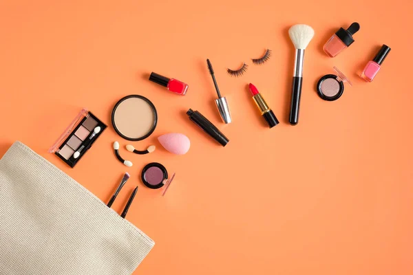 Make-up-Produkte verschüttet aus Kosmetiktasche auf pastellfarbenem Hintergrund Pfirsich. flache Lage, Draufsicht. Stylische Make-up-Artist-Tasche mit Beauty-Produkten — Stockfoto