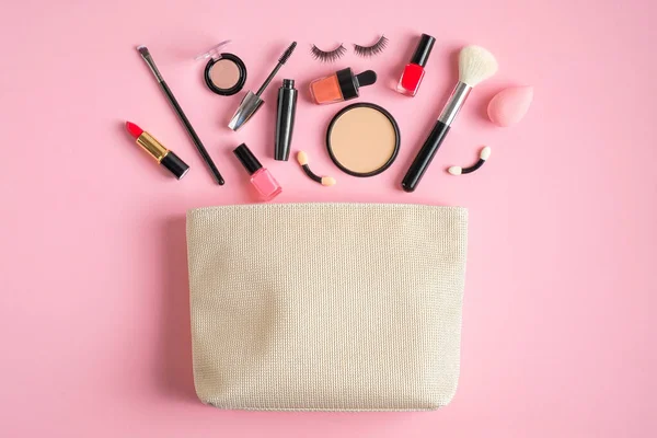 Cosmetic bag and makeup products spilling out on pink background. Flat lay, top view — Stok fotoğraf