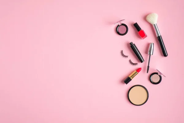 Prodotti per il trucco e cosmetici che si rovesciano su sfondo rosa pastello. Posa piatta, vista dall'alto, copiare spazio. Concetto di trucco donna . — Foto Stock