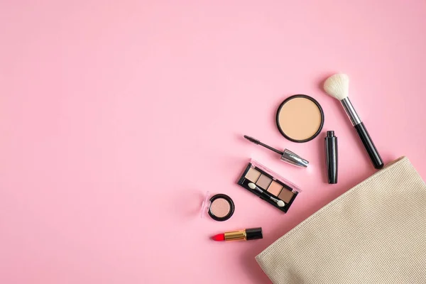 Smink táska kozmetikai termékek ömlött ki a pasztell rózsaszín háttér. Lapos fekvés, csúcskilátás. Stílusos make up művész tasak szépségápolási termékek — Stock Fotó